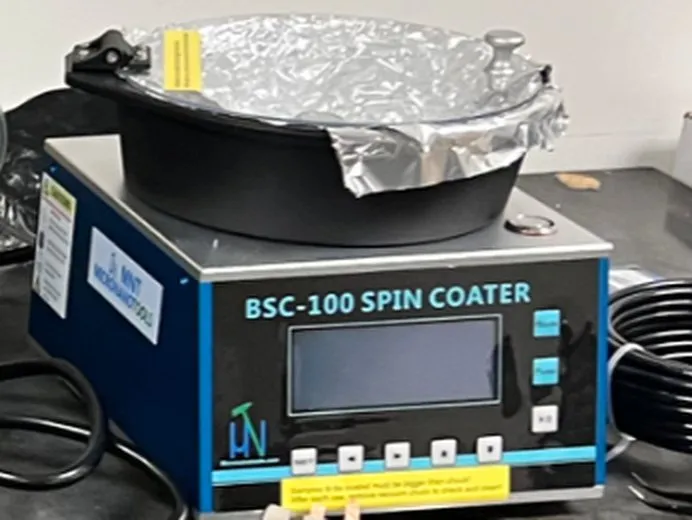 Holmarc BSC-100 spin coater and vacuum pump for thin-film deposition in the Bioelectronic Synergy Lab.